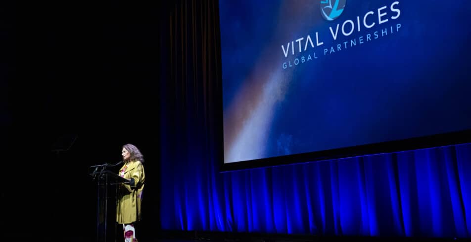 Addressing the audience beneath the Vital Voices banner, a moment of inspiration unfolds.