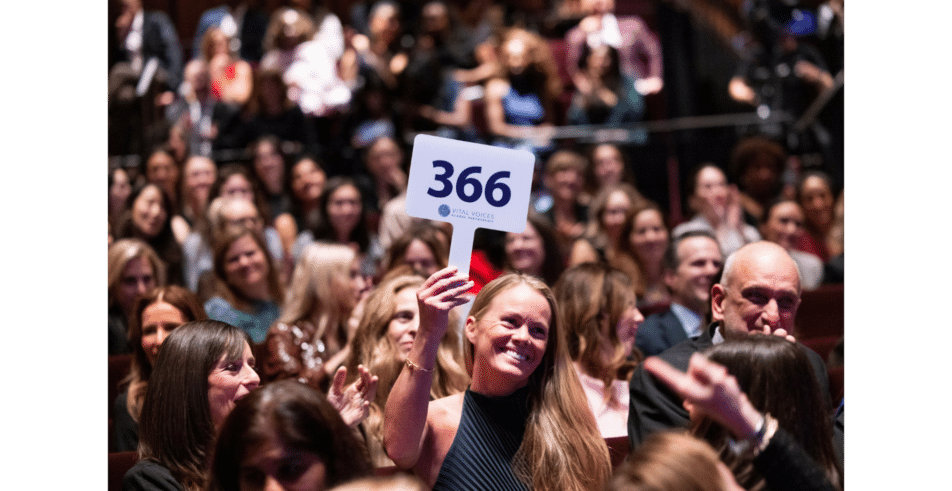 A live auction participant proudly raises her paddle to donate to the Vital Voices mission.